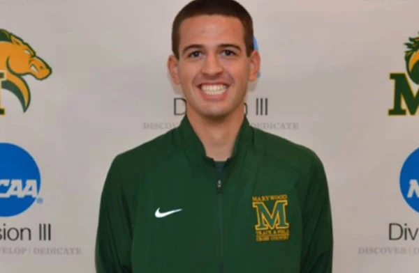 A smiling man standing in front of a Marywood Pacers backdrop.